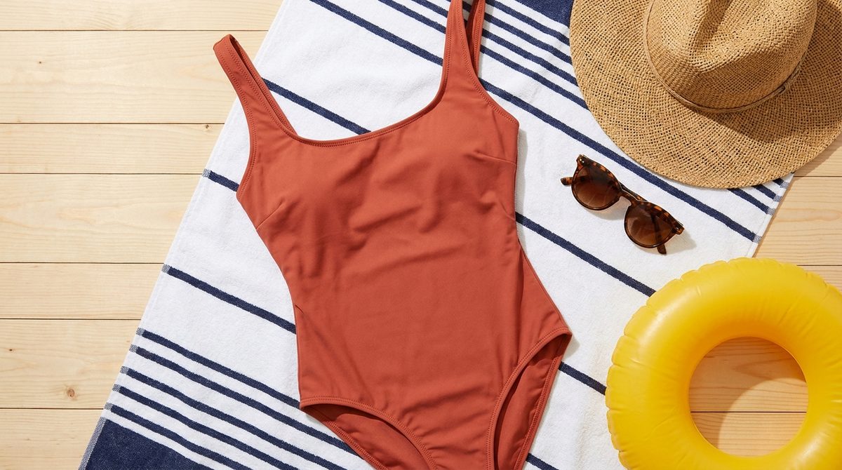 Malla enteriza sobre toalla de rayas con sombrero de paja y anteojos de sol, regalo de verano para mujeres